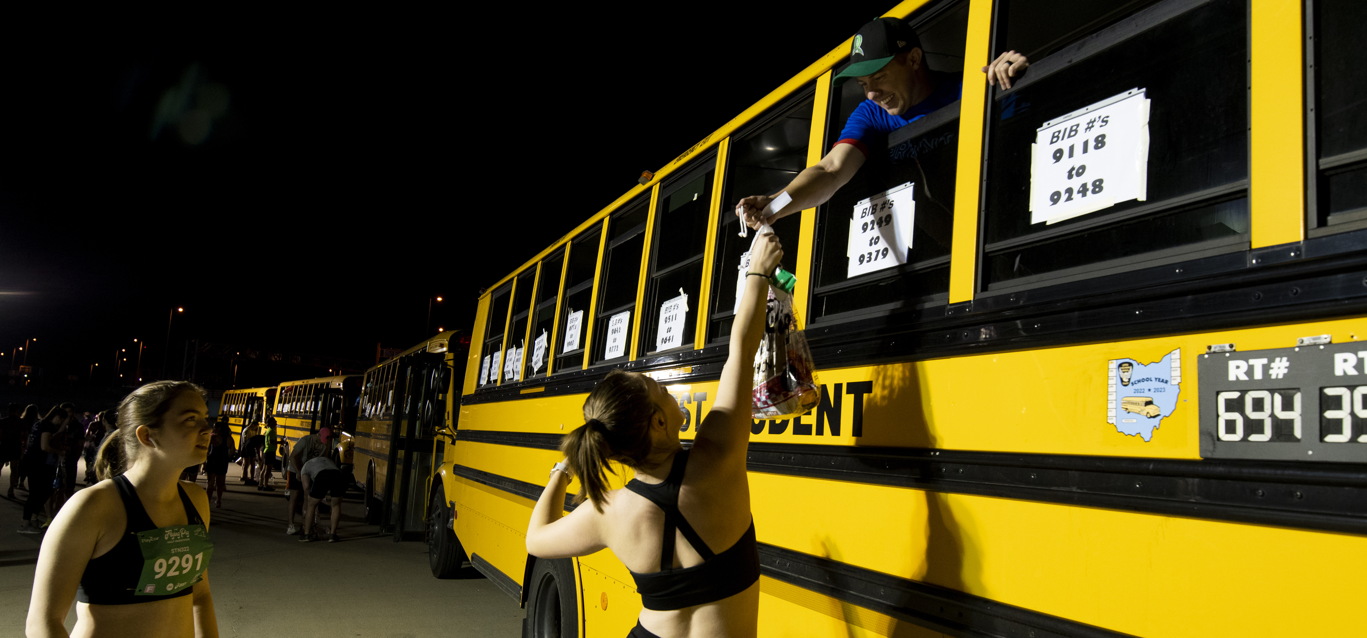 race participant handing over their gear check bag to the volunteer through the baggage bus window